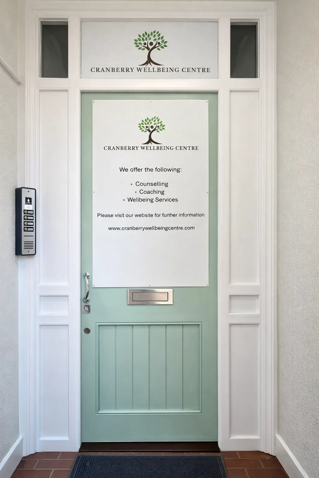 The sage-green front door at the Cranberry Wellbeing Centre, with the intercom on the left
